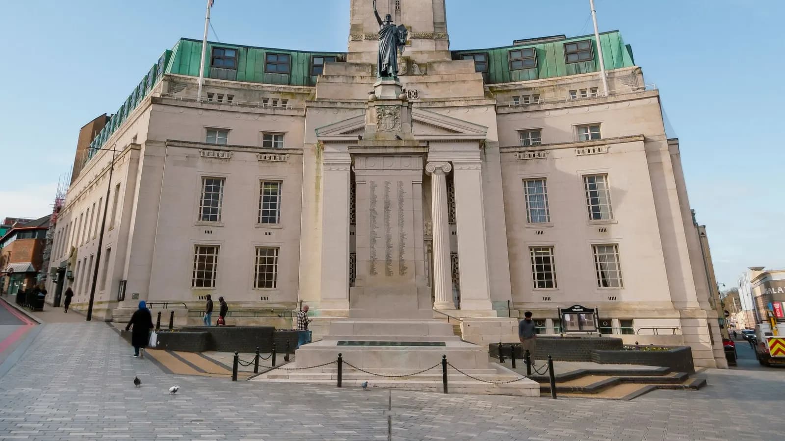 The stone frontage of Luton Town Hall with a war memorial and paved square in front