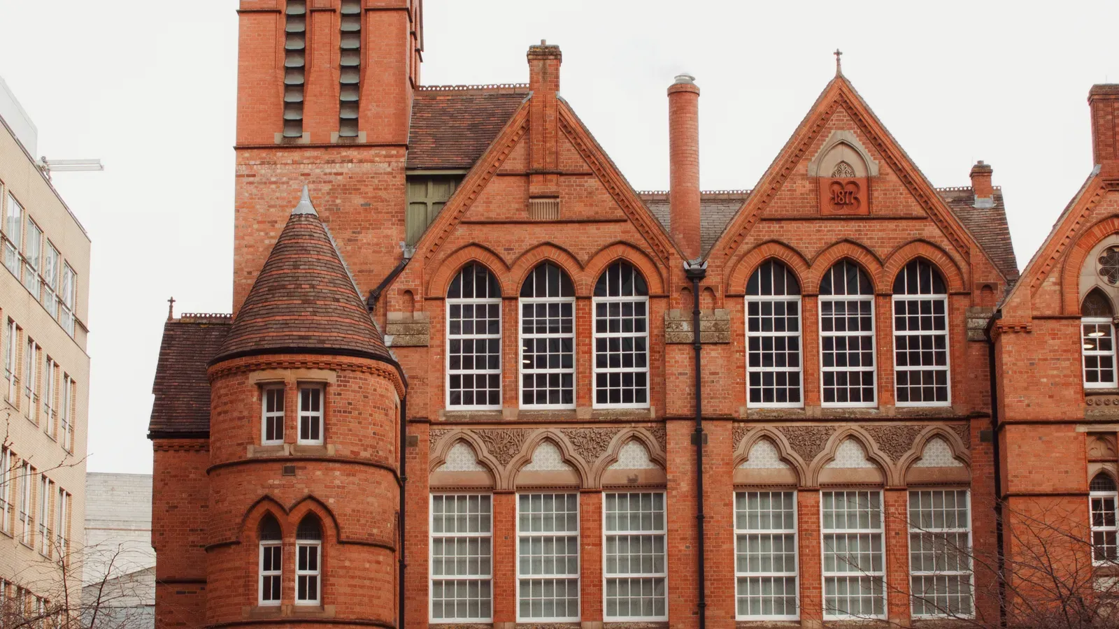 Victorian red-brick building in Birmingham with twin gables, arched sash windows and a round tiled turret
