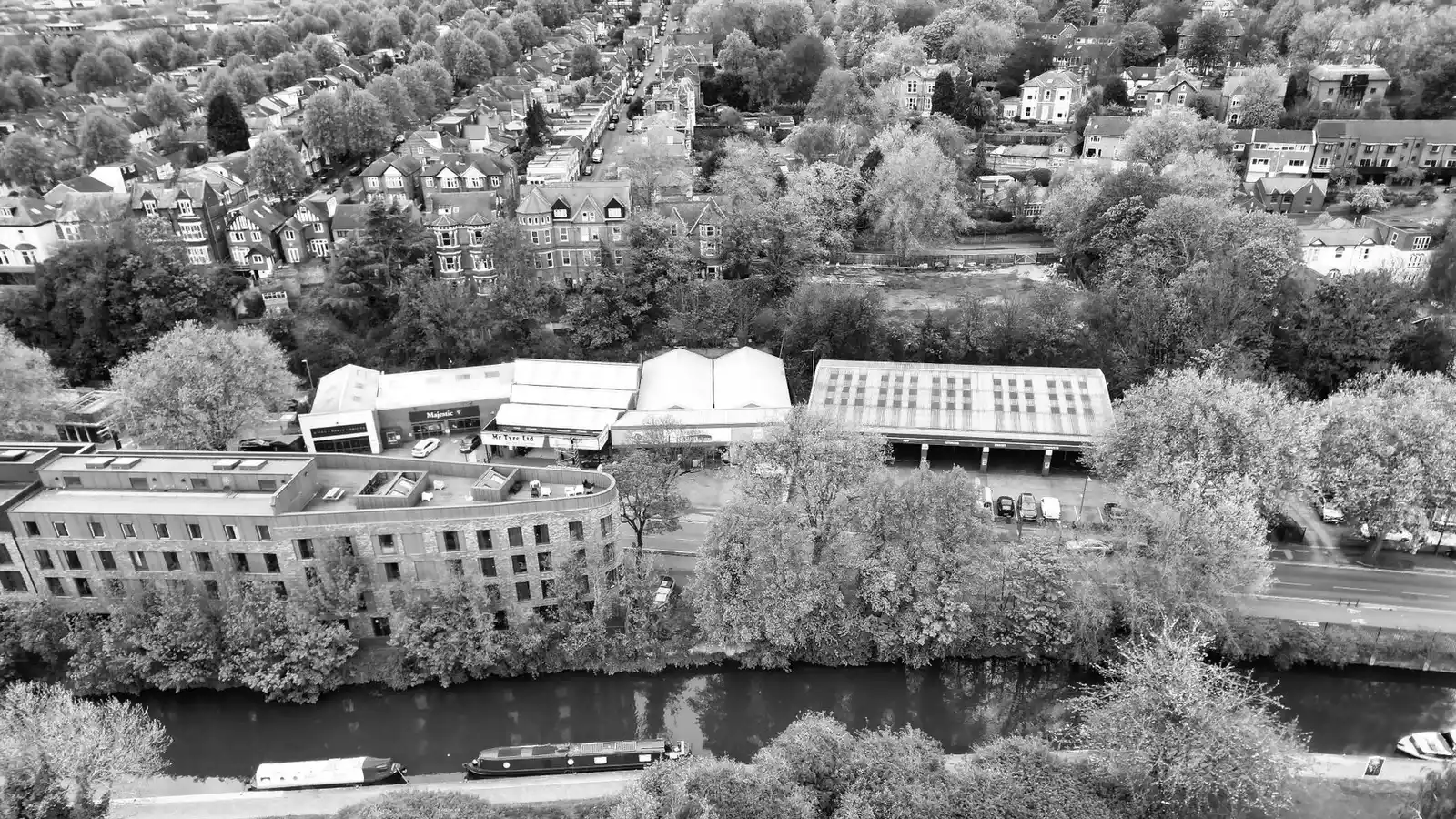 Black and white aerial view over the Nottingham canal and a tree-lined road, with Edwardian brick villas and gabled houses at the top of the frame